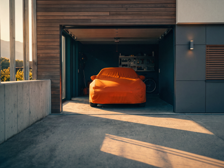 Abgedecktes Auto in einer offenen Garage eines Einfamilienhauses