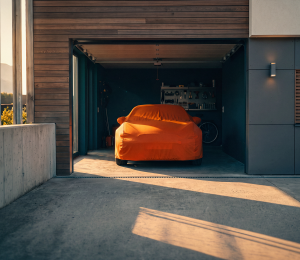 Abgedecktes Auto in einer offenen Garage eines Einfamilienhauses