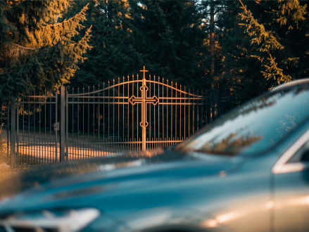 Auto vor dem verschlossenen Tor eines Friedhofs