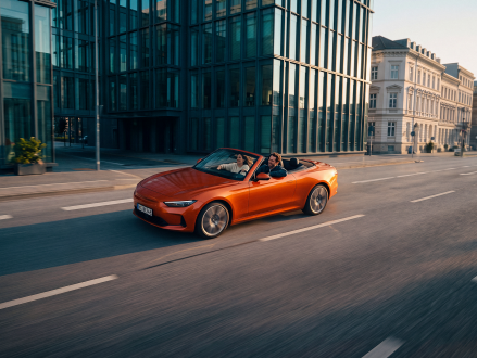 Orangefarbenes Cabriolet bei einer Fahrt durch eine moderne Innenstadt