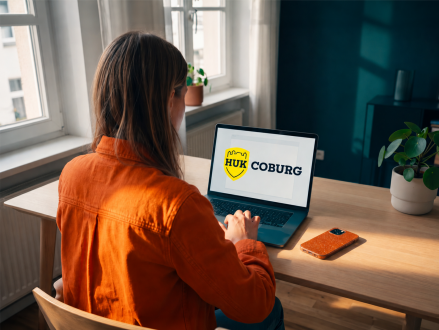 Frau nutzt einen Laptop mit geöffneter HUK-Coburg Website