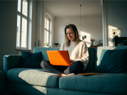 Frau nutzt einen Laptop auf dem Sofa im Wohnzimmer