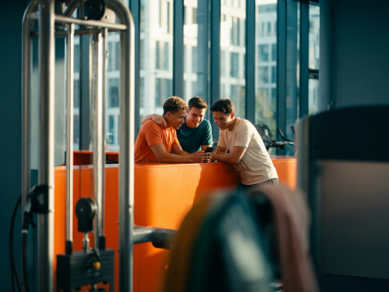 Drei Freunde unterhalten sich beim gemeinsamen Training im Fitnessstudio