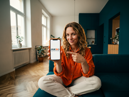 Kundin zeigt das HUK24 Logo auf ihrem Smartphone