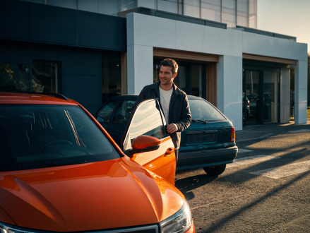 Mann steht zwischen zwei Autos bei einem Fahrzeugwechsel