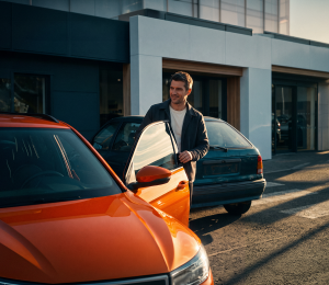 Mann steht zwischen zwei Autos bei einem Fahrzeugwechsel