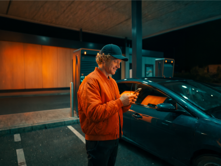 Mann bedient eine Ladestation für ein Elektroauto per Smartphone