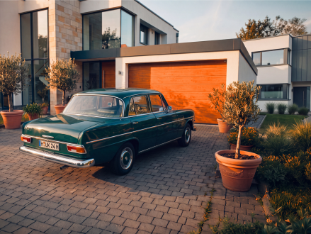 Klassischer Oldtimer steht vor der Garage eines Einfamilienhauses