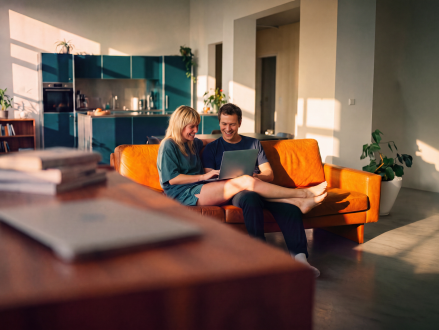 Paar nutzt gemeinsam einen Laptop auf dem Sofa zu Hause