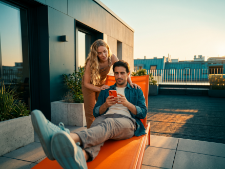 Paar betrachtet gemeinsam ein Smartphone auf einer Dachterrasse