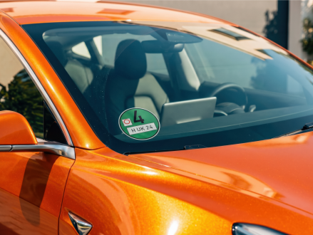 Grüne Umweltplakette an der Windschutzscheibe eines orangefarbenen Autos
