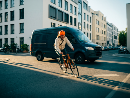 Radfahrer fährt auf einer Stadtstraße an einem Transporter vorbei