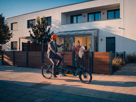 Vater fährt mit einem Lastenrad vor dem Wohnhaus seiner Familie
