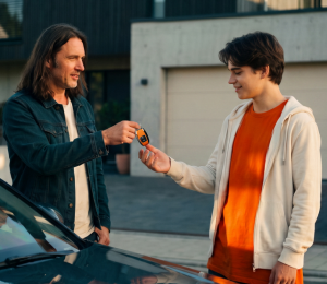 Übergabe eines Autoschlüssels zwischen zwei Personen neben einem Auto