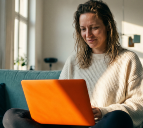 Frau nutzt einen Laptop auf dem Sofa im Wohnzimmer