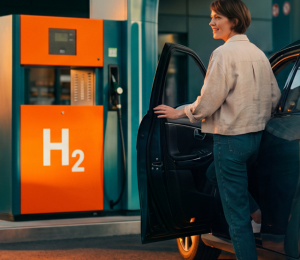 Frau betankt ein Auto an einer Wasserstofftankstelle