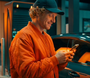 Mann bedient eine Ladestation für ein Elektroauto per Smartphone