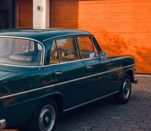 Klassischer Oldtimer steht vor der Garage eines Einfamilienhauses