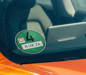 Grüne Umweltplakette an der Windschutzscheibe eines orangefarbenen Autos