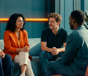 Mitarbeitende sitzen bei einem Teammeeting gemeinsam in einer Bürolounge